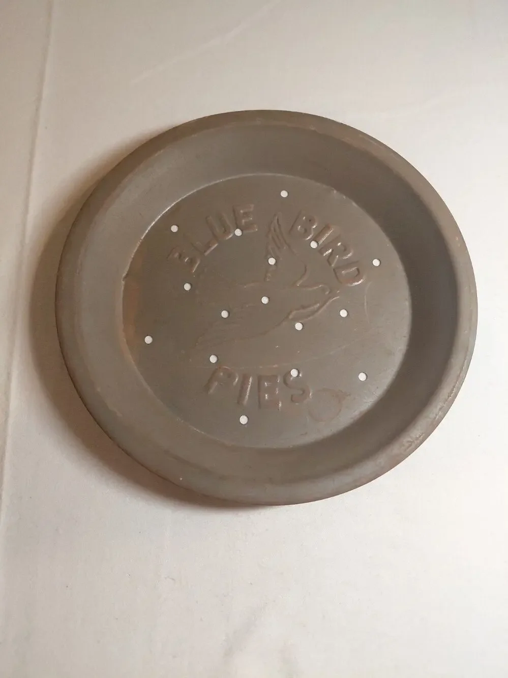 vintage Blue Bird Pies metal pie tin featuring embossed lettering and vent holes